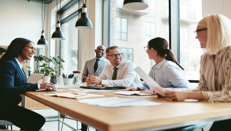 Diverse business people laughing during a meeting around an office