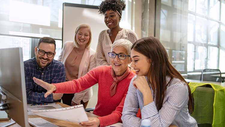 Fundraising Consultant Pointing to Monitor Surrounded by a Group of Fundraisers