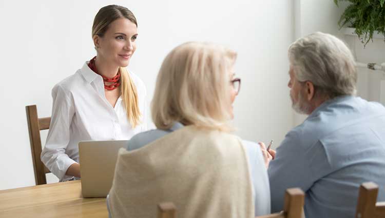 Female fundraiser interviewing older donor couple