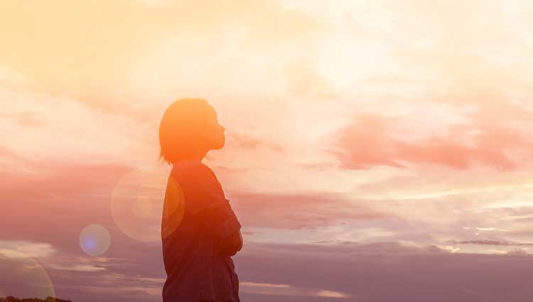 Silhouette of person looking upward against warm sunset sky, symbolizing hope and vision in faith-based fundraising transformation
